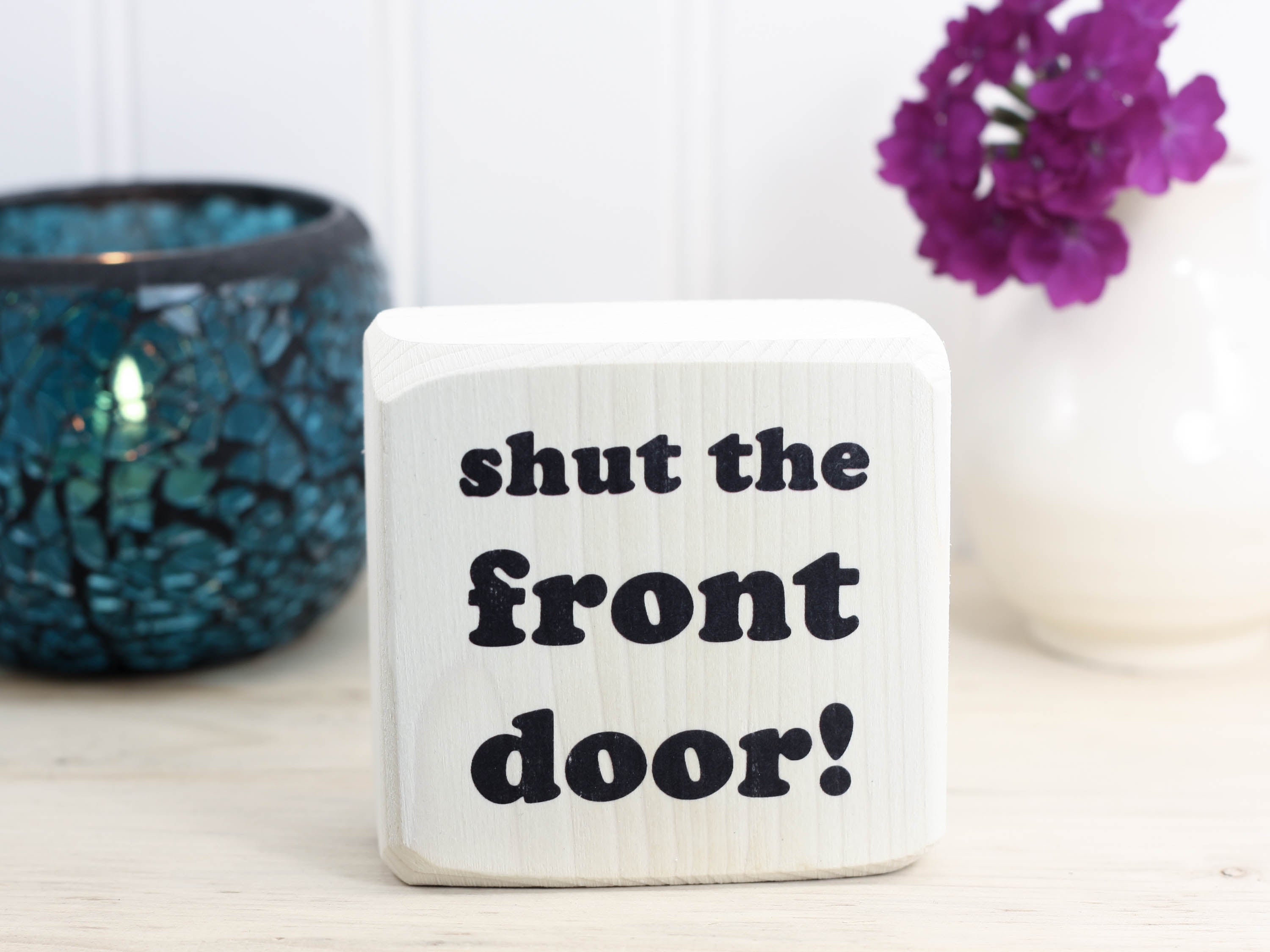 Small, freestanding, whitewashed, solid wood sign with funny saying "shut the front door!"