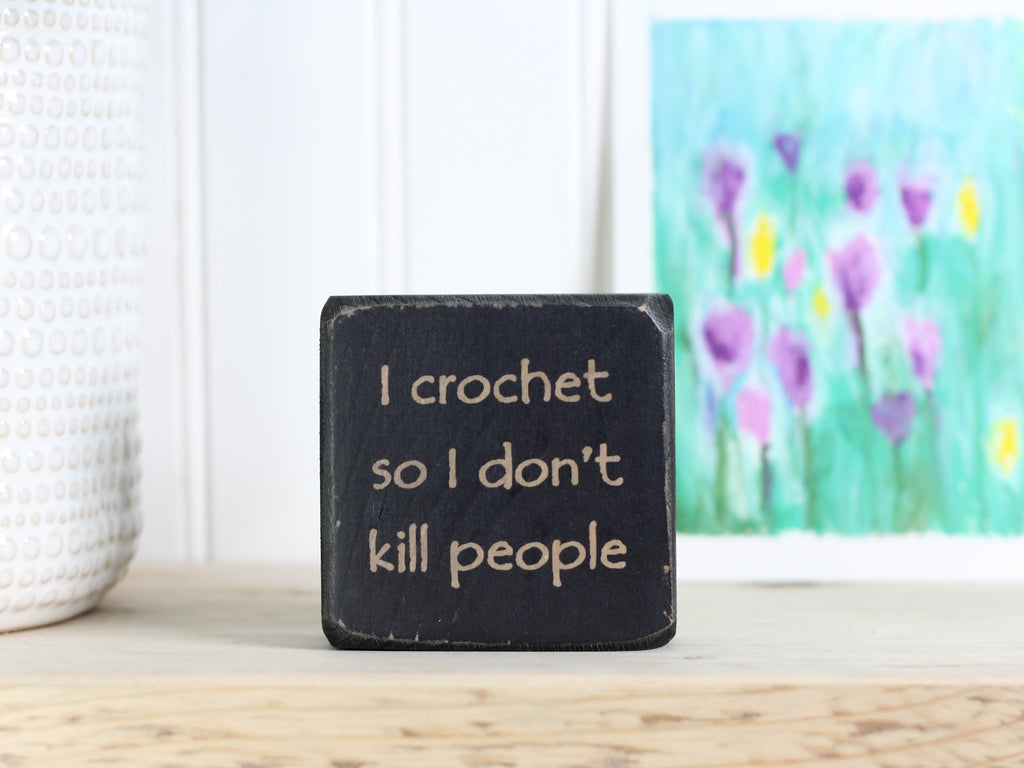 mini wood sign in distressed black with the text "I crochet so I don't kill people"