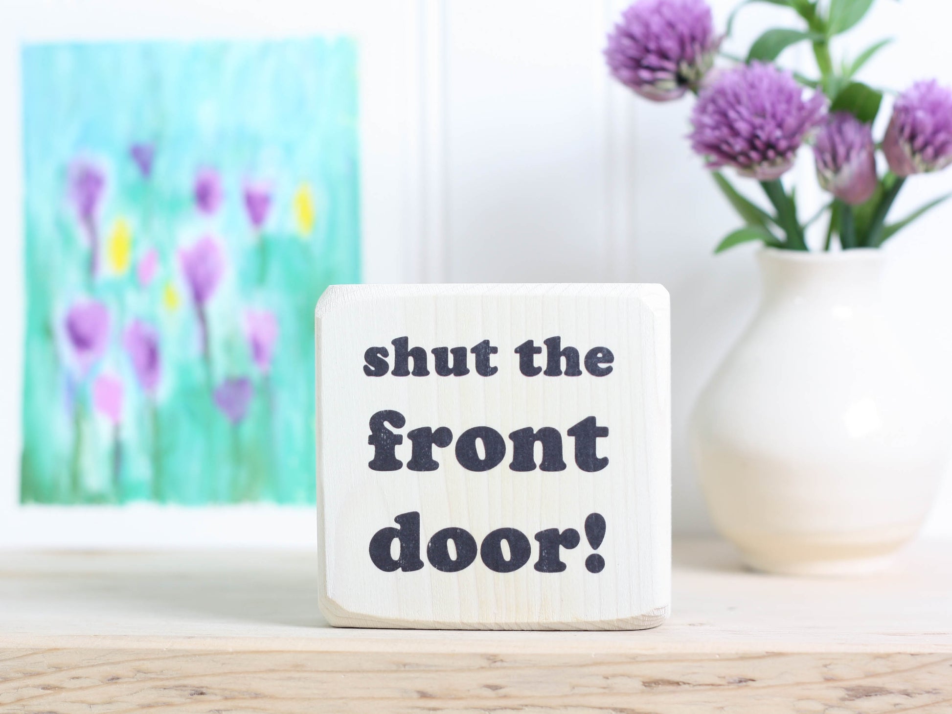 Small, freestanding, whitewashed, solid wood sign with funny saying "shut the front door!"