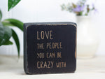 Mini quote block in distressed black with the saying "Love the people you can be crazy with."