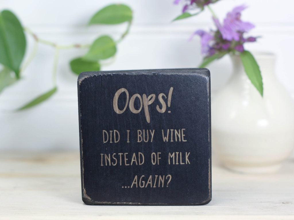 Mini wood bar sign in distressed black with the saying "Oops! Did I buy wine instead of milk...again?"