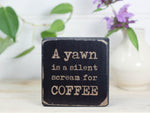 Funny kitchen sign in distressed black with the saying "A yawn is a silent scream for coffee".