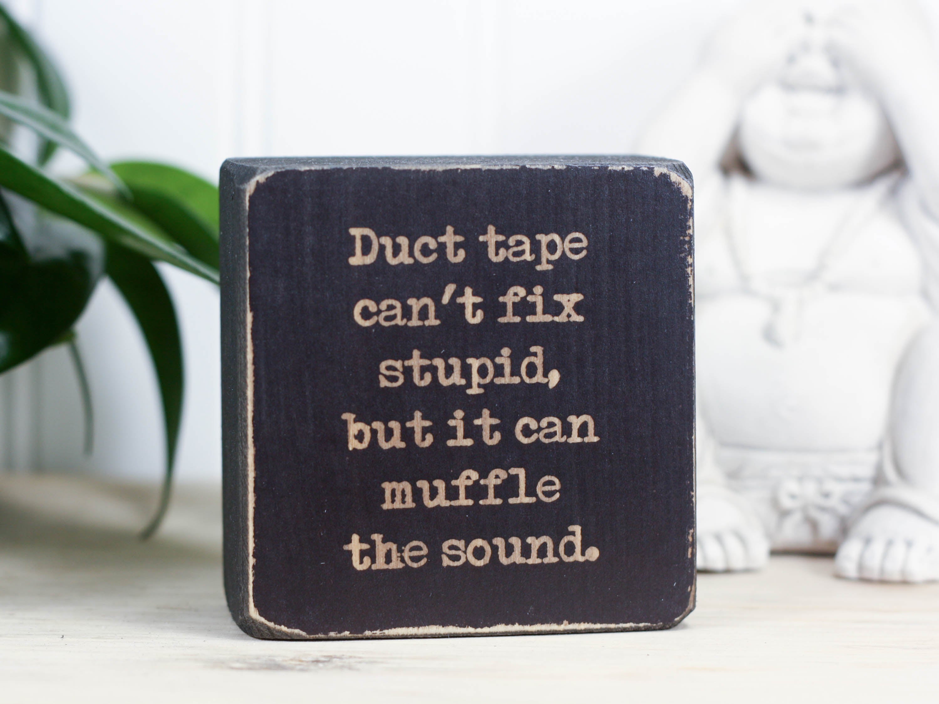 Small, freestanding, distressed black, solid wood sign with funny saying "Duct tape can't fix stupid, but it can muffle the sound."