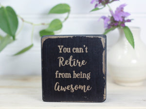 Mini wood sign in distressed black with the saying "You can't retire from being awesome".