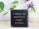 Mini wood sign in distressed black with the saying "I think my guardian angel drinks." Funny home decor.
