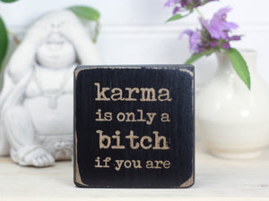 Small but sassy freestanding decor in distressed black with the saying "Karma is only a bitch if you are".