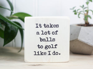 Small wooden sign in whitewash with the saying "It takes alot of balls to golf like I do."