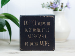 Small, freestanding, distressed black, solid wood sign, with funny saying "Coffee keeps me busy until it is acceptable to drink wine."