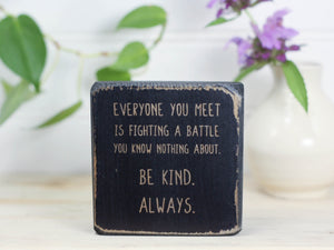 Small freestanding wood decor in distressed black with the saying "Everyone you meet is fighting a battle you know nothing about. Be kind. Always"