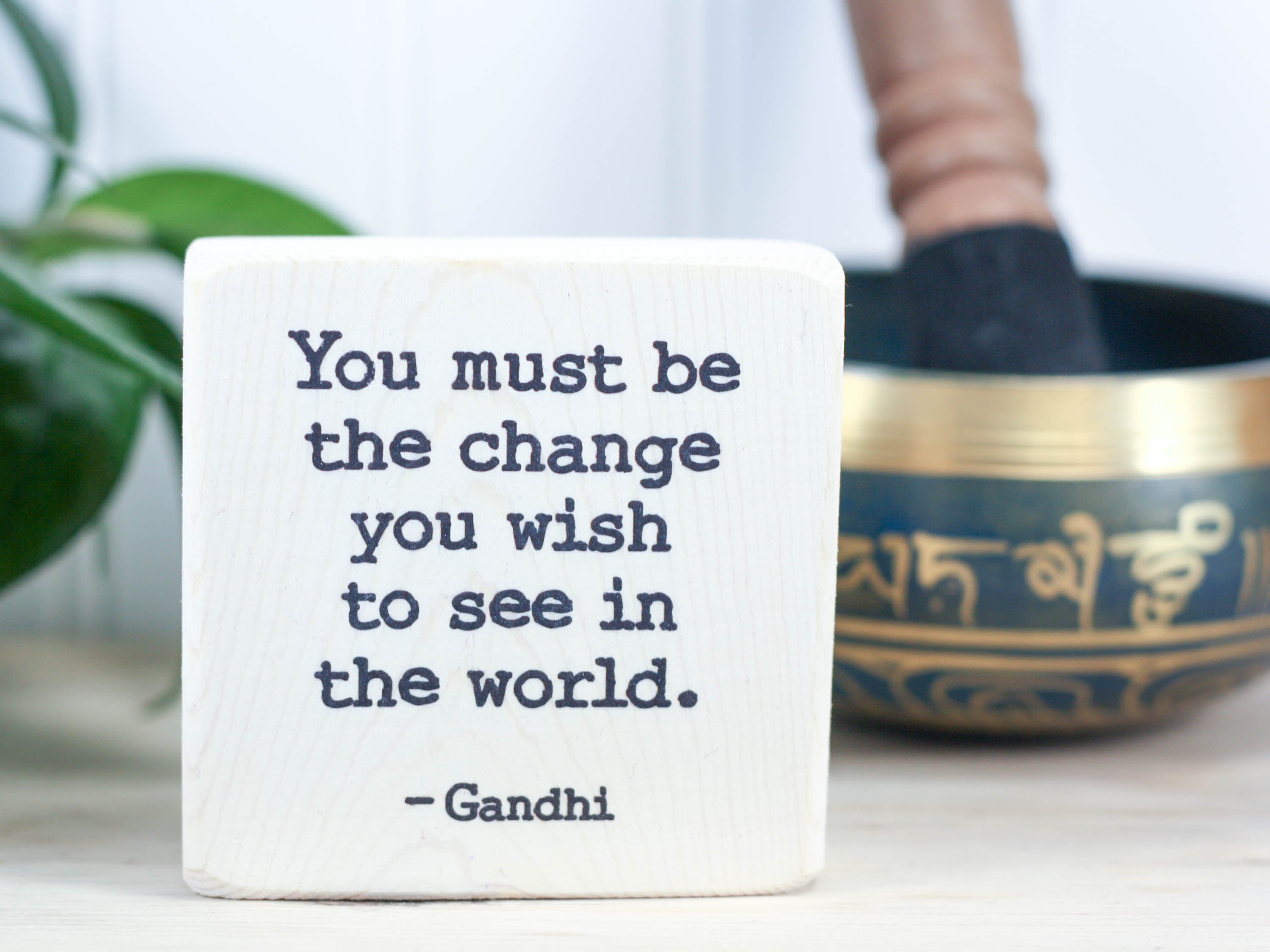 Small quote block in whitewash with the saying "You must be the change you wish to see in this world. -Gandhi"