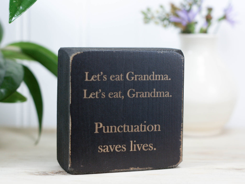 Mini wood sign in distressed black with the saying "Let's eat Grandma. Let's eat, Grandma. Punctuation saves lives."