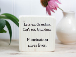 Mini wood sign in whitewash with the saying "Let's eat Grandma. Let's eat, Grandma. Punctuation saves lives."