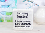 Small wood sign in whitewash with the saying "Too many books? I think you mean not enough bookshelves."