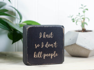 Small, freestanding, distressed black, solid wood sign with a funny saying on it "I knit so I don't kill people".