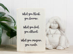 Small whitewashed wood block sign with the text "What you think, you become. What you feel, you attract. What you imagine, you create."