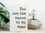 Small wood romance sign in whitewash with the saying "You are the bacon to my eggs".