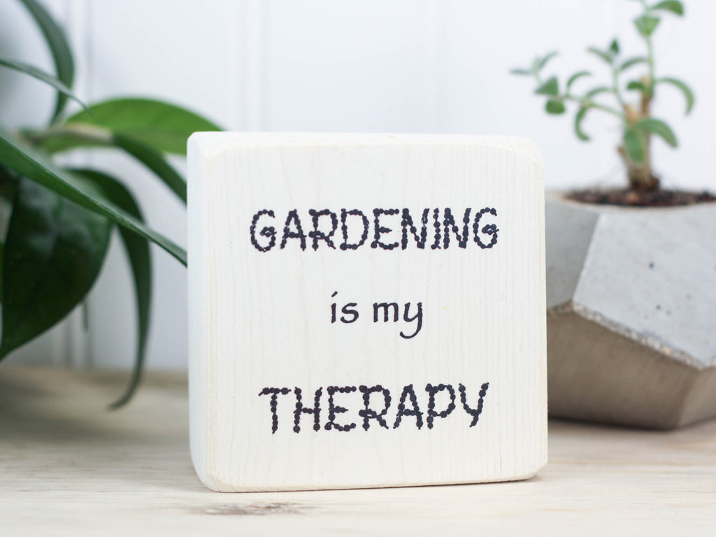 Small, freestanding, whitewash, solid wood sign with saying "Gardening is my therapy".