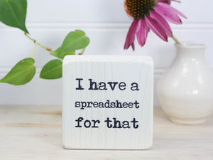 Small wood sign in whitewash with the saying "I have a spreadsheet for that."