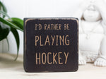 Mini wood sign in distressed black with the saying "I'd rather be playing hockey".