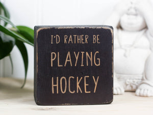 Mini wood sign in distressed black with the saying "I'd rather be playing hockey".