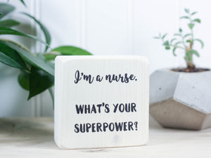 Mini wood sign in whitewash with the saying "I'm a nurse. What's your superpower?"