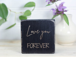 Small wooden sign in distressed black with the saying "Love you forever".