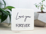 Small wooden sign in whitewash with the saying "Love you forever".