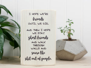 Small wood sign in whitewash with the saying "I hope we're friends until we die. And then I hope we stay ghost friends and walk through walls and scare the shit out of people."