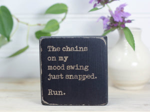 Small wood sign in distressed black with the saying "The chains on my mood swing just snapped. Run."