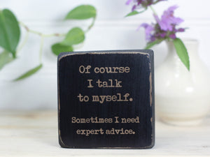 Small wood sign in distressed black with the saying "Of course I talk to myself. Sometimes I need expert advice."