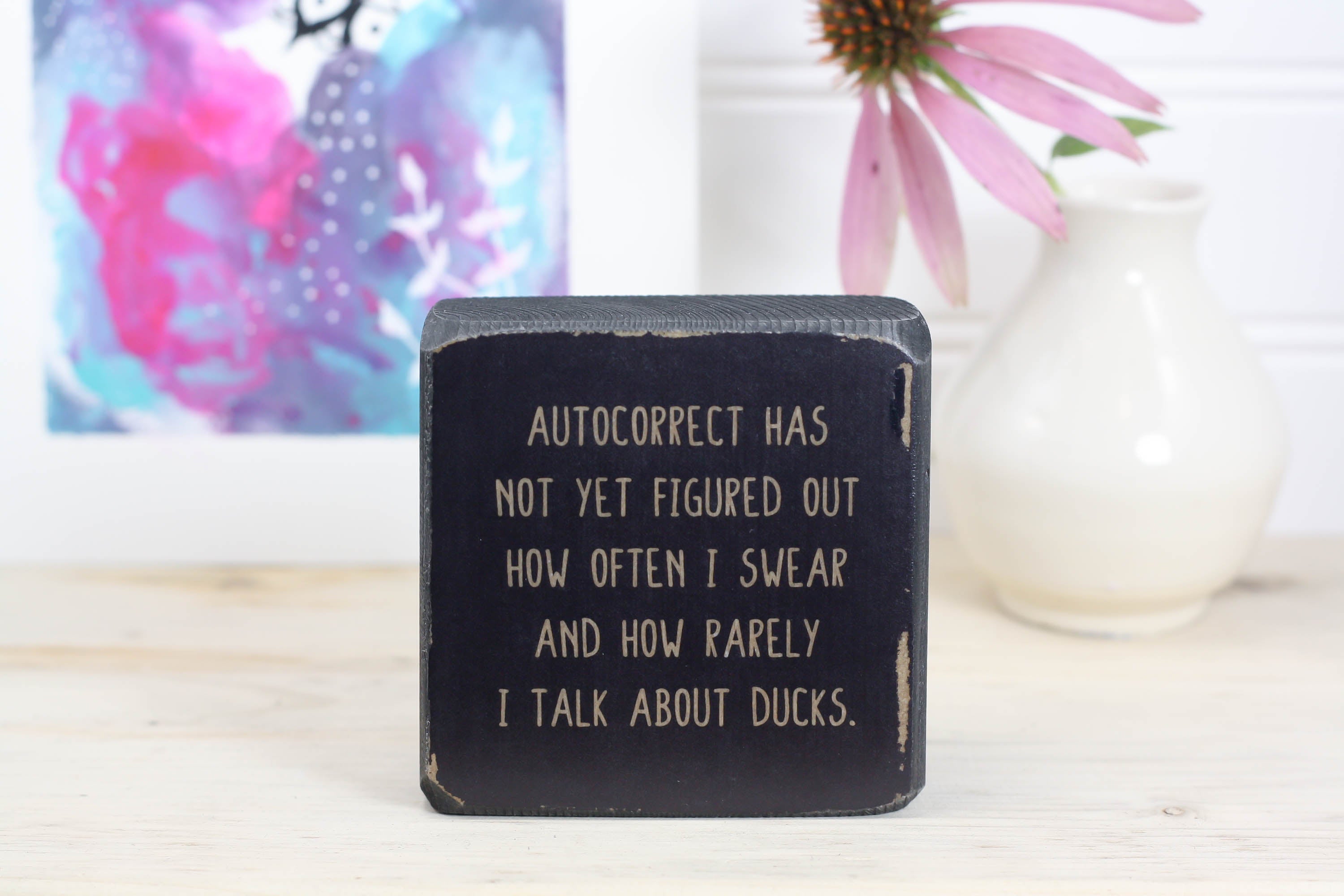 Small, freestanding, distressed black, solid wood sign with saying "autocorrect has not yet figured out how often I swear and how rarely I talk about ducks."