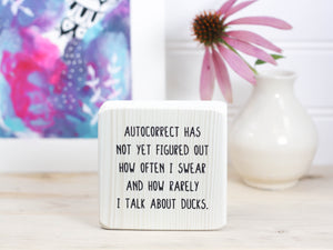 Small, freestanding, whitewash, solid wood sign with saying "autocorrect has not yet figured out how often I swear and how rarely I talk about ducks."