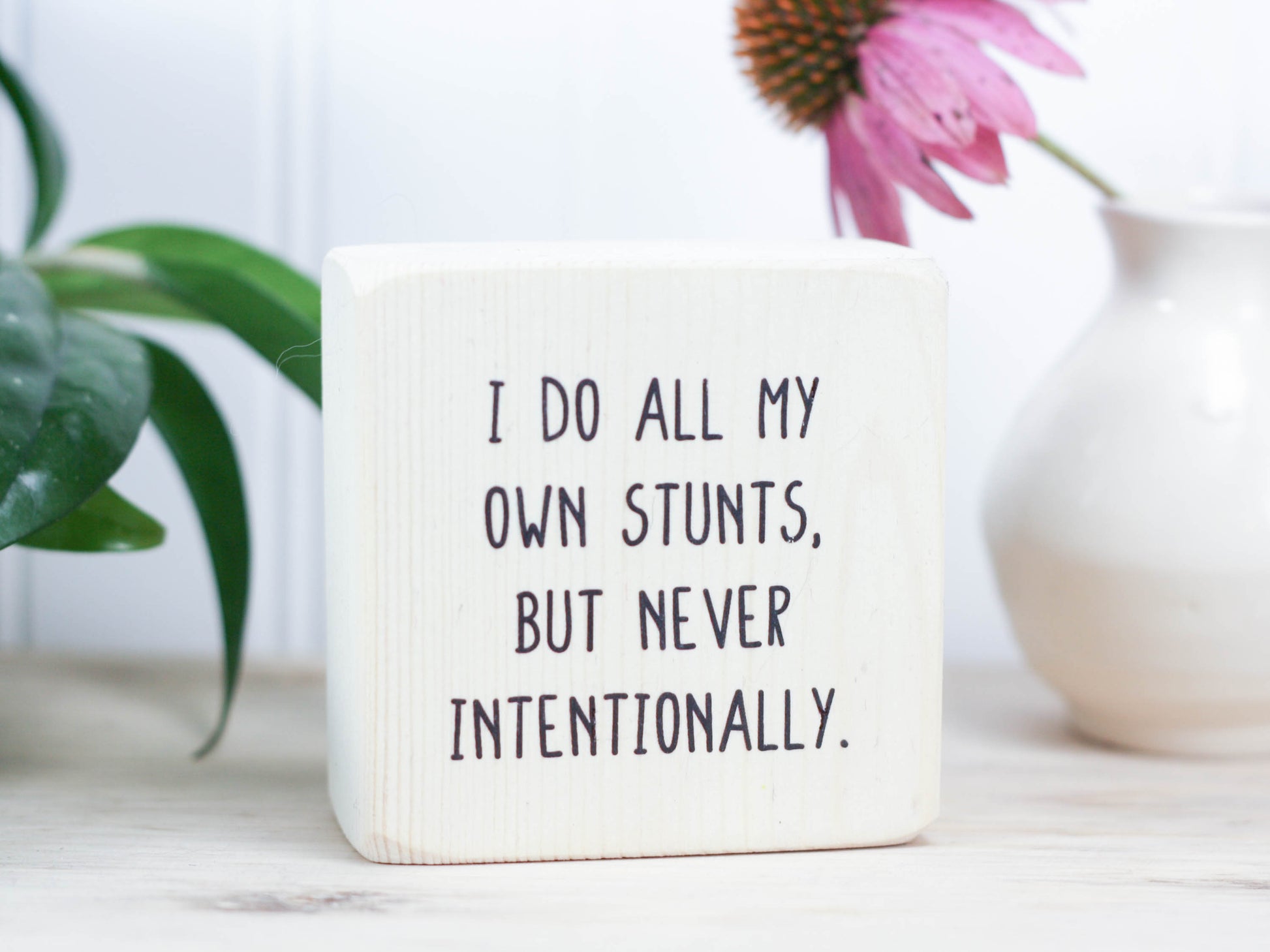 Small, freestanding, whitewash, solid wood sign with funny saying on it "I do all my own stunts, but never intentionally."