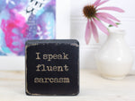 Mini wood sign in distressed black with the saying "I speak fluent sarcasm".