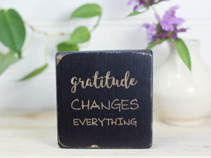 Inspirational mini wood block in distressed black with the saying "Gratitude changes everything".