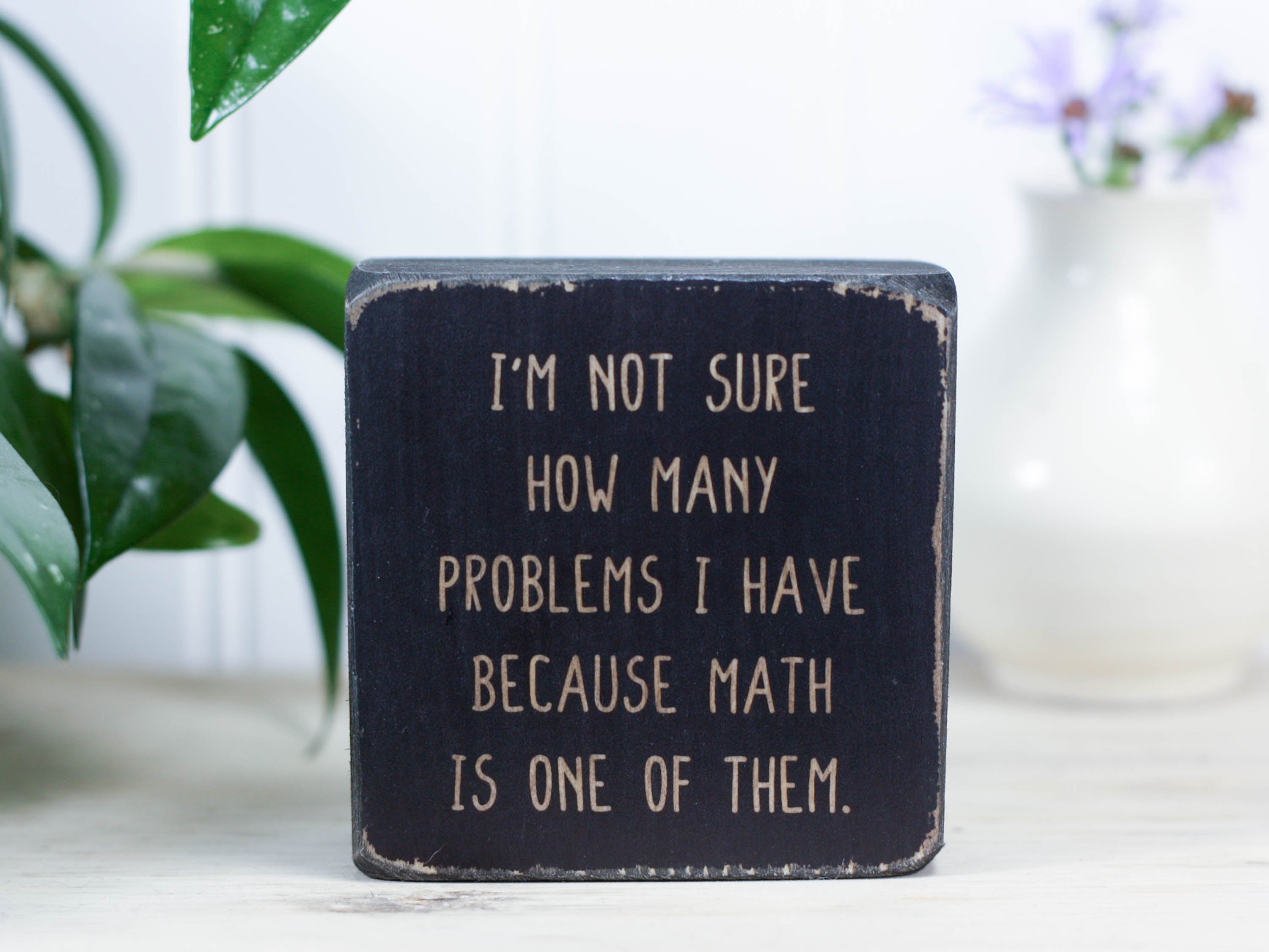 Mini wood sign in distressed black with the saying "I'm not sure how many problems I have because math is one of them."