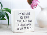Mini wood sign in whitewash with the saying "I'm not sure how many problems I have because math is one of them."
