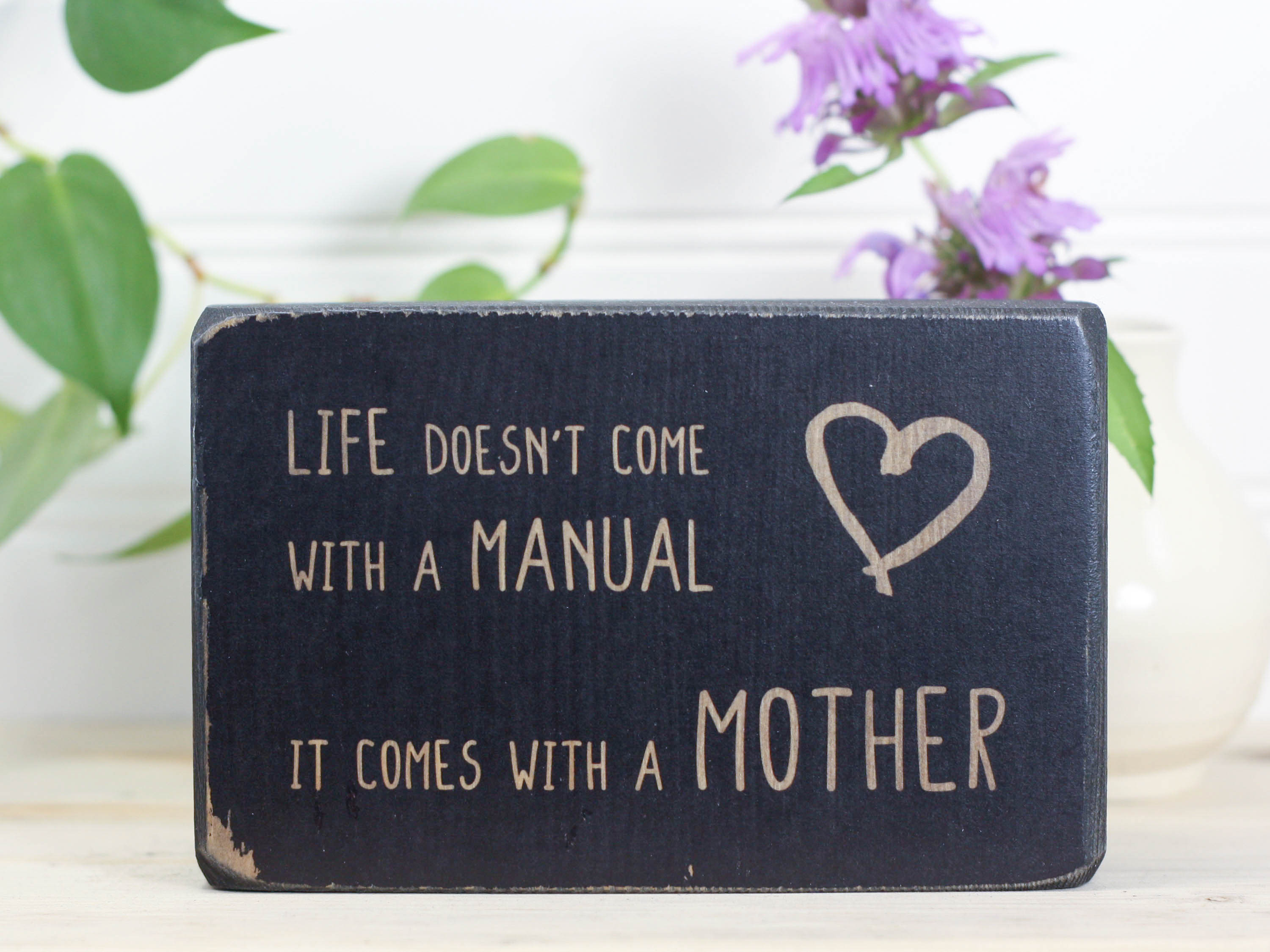 Small wood decor sign in distressed black with the saying "Life doesn't come with a manual. It comes with a mother."