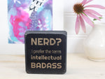Small desk sign in distressed black with the saying "Nerd? I prefer the term intellectual badass."