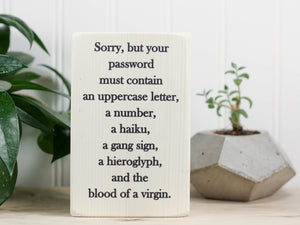 Small funny wood sign in whitewash with the saying "Sorry, but your password must contain an uppercase letter, a number, a haiku, a gang sign, a hieroglyph, and the blood of a virgin."