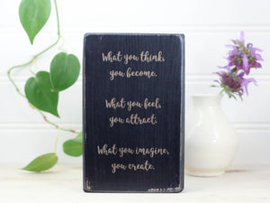 Small distressed black wood block sign with the text "What you think, you become. What you feel, you attract. What you imagine, you create."
