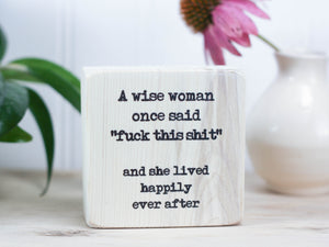 Small freestanding whitewashed wood sign with the saying "A wise woman once said "fuck this shit" and she lived happily ever after