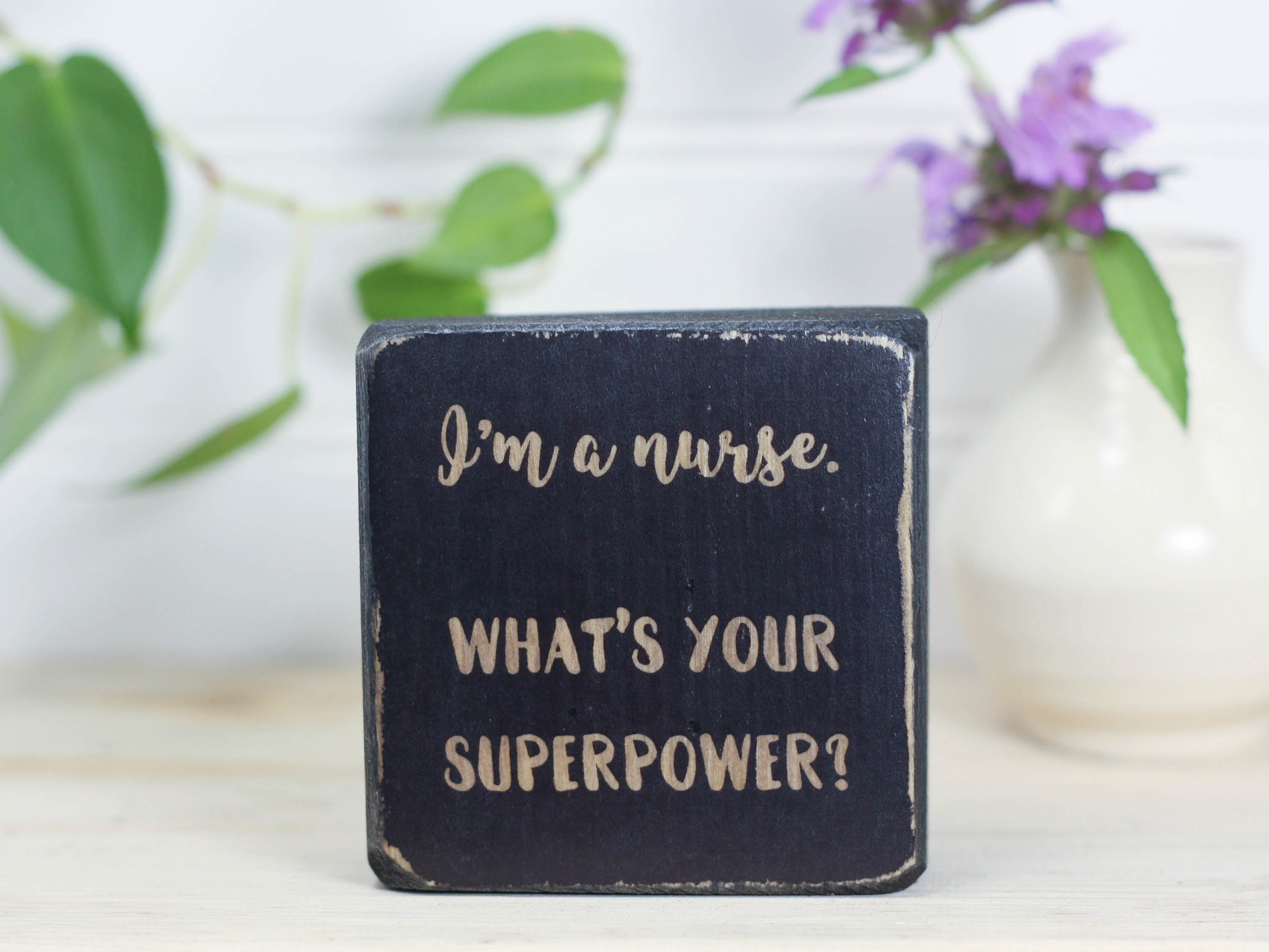 Mini wood sign in distressed black with the saying "I'm a nurse. What's your superpower?"
