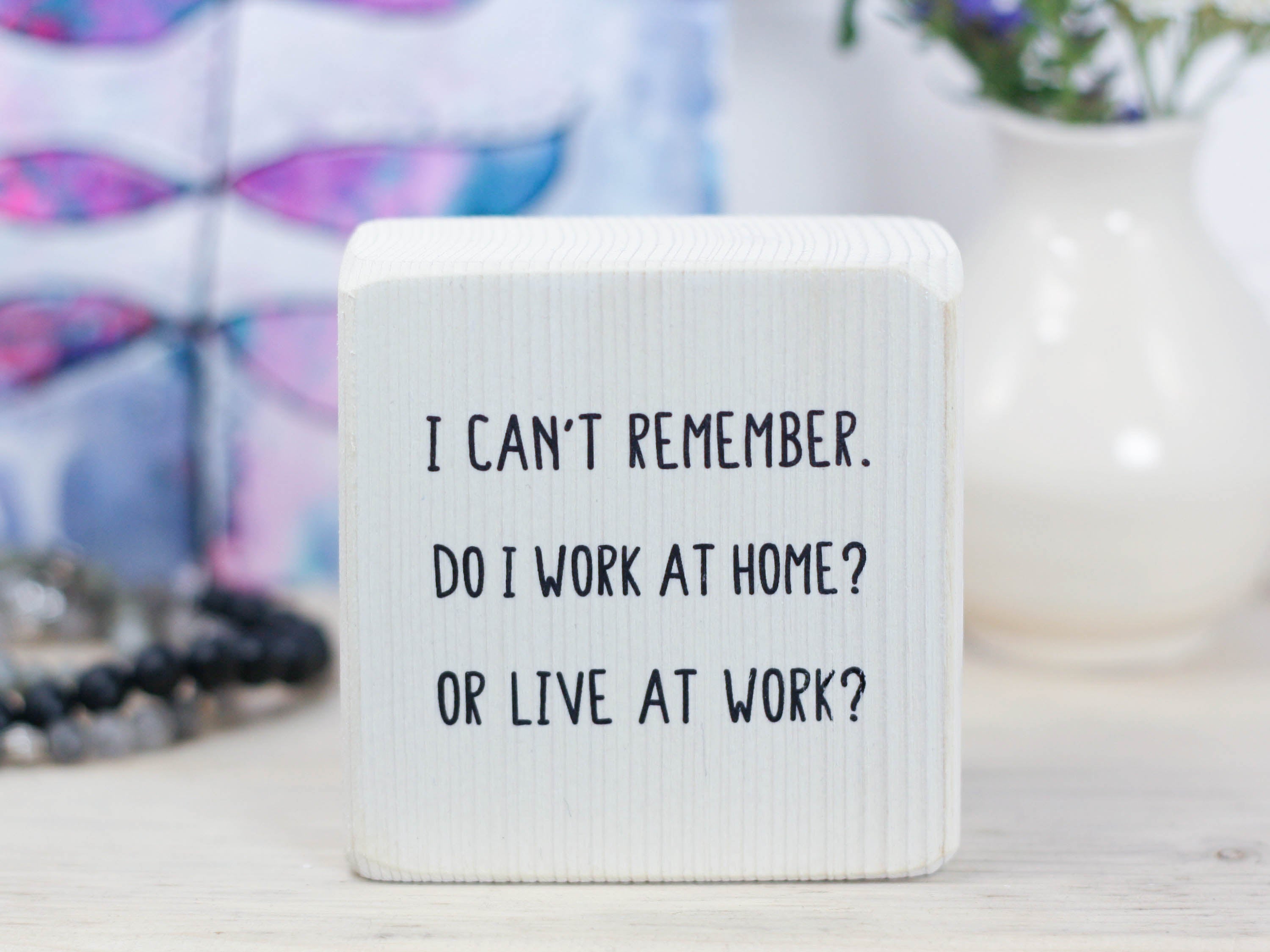 Small, freestanding whitewash wood sign with a funny saying on it "I can't remember. Do I work at home? Or live at work?"