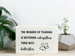 Small wood teacher gift in whitewash with the saying "The wonder of teaching is watching caterpillars turn into butterflies."