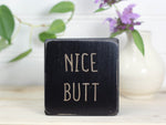 Small wood sign in distressed black with the text "nice butt" on it