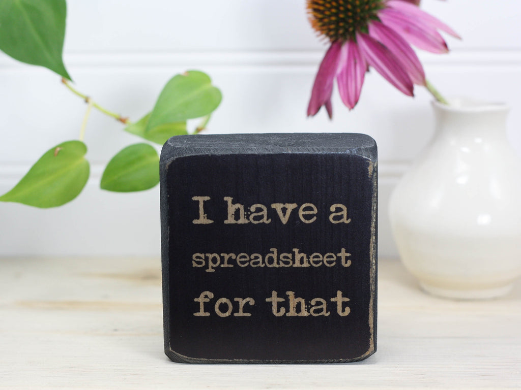 Small wood sign in distressed black with the saying "I have a spreadsheet for that."