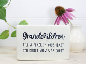 Small whitewashed wooden sign with the saying "Grandchildren fill a place in your heart you didn't know was empty. "