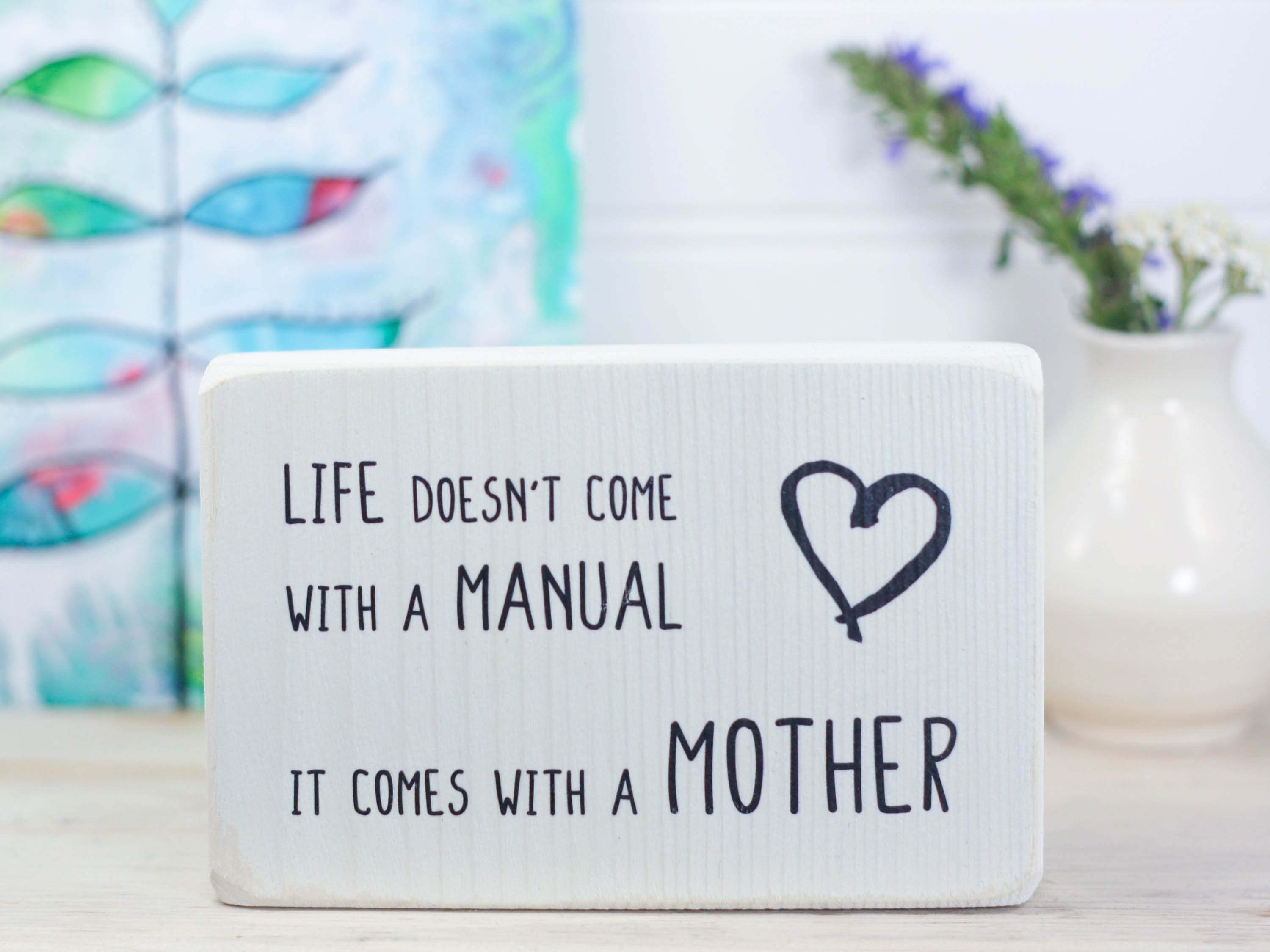 Small wood decor sign in whitewash with the saying "Life doesn't come with a manual. It comes with a mother."