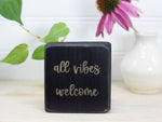 Small wood sign in distressed black with the saying "all vibes welcome"